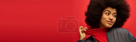 Téléchargez les photos : Une femme avec coiffure bouclée tient une écharpe rouge vibrante dans une pose à la mode. - en image libre de droit