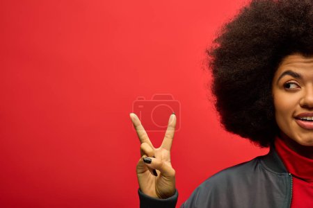 Mujer afroamericana con estilo en traje de moda, haciendo señal de paz con los dedos.