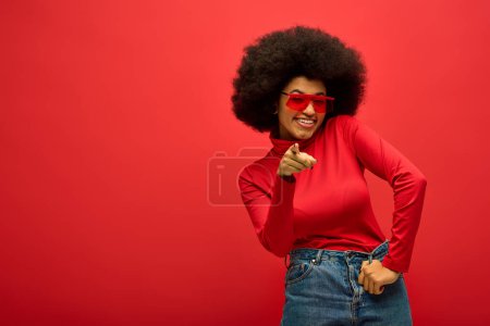 Téléchargez les photos : Trendy African American woman posing in a vibrant backdrop, wearing a red shirt and sunglasses. - en image libre de droit