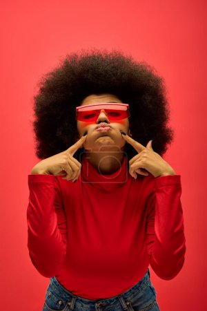Stilvolle Afroamerikanerin in rotem Hemd und Brille posiert.