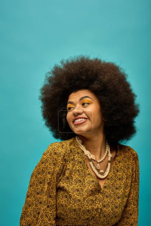 Foto de Elegante mujer afroamericana con cabello rizado sonriendo brillantemente para la cámara. - Imagen libre de derechos