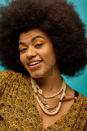 Téléchargez les photos : Femme afro-américaine vibrante avec des cheveux bouclés souriant en tenue tendance. - en image libre de droit