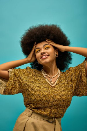 Stilvolle Afroamerikanerin mit voluminösem Afro posiert modisch vor lebendigem Hintergrund.