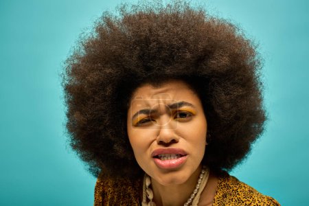 Une femme afro-américaine élégante en tenue tendance, avec coiffure bouclée, semble surprise.
