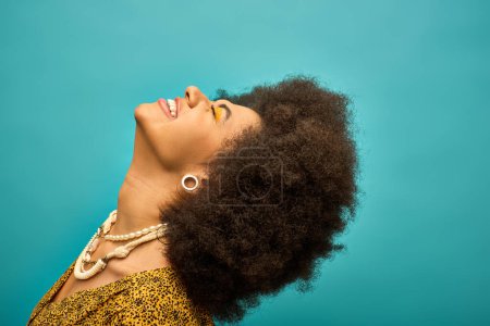 Eine stylische Afroamerikanerin mit lockigem Haar blickt in einer lebendigen Szene in den Himmel.