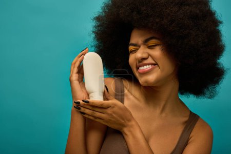 Stylish African American woman with curly hairdohair, holding a hair dryer in a trendy pose.