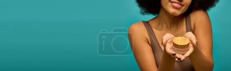 Foto de Elegante mujer afroamericana sosteniendo crema en su mano derecha. - Imagen libre de derechos