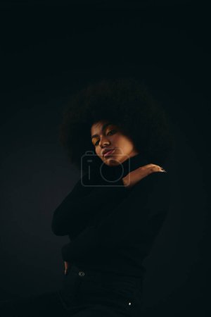 Photo for Stylish African American woman stands in the dark. - Royalty Free Image