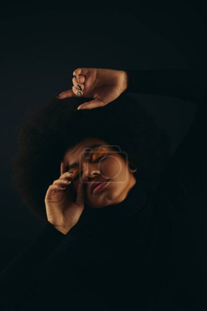 Mujer afroamericana en traje negro posando activamente.