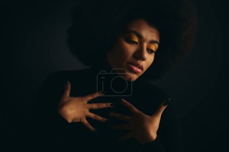 Stylish African American woman reaching out into darkness in fashionable attire.