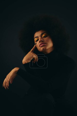Stylish African American woman with curly hairdoposes against vibrant backdrop.
