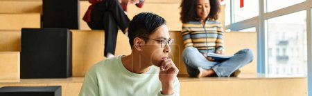 Téléchargez les photos : Un homme d'ascendance afro-américaine est assis dans les escaliers d'un bâtiment universitaire, profondément réfléchi - en image libre de droit