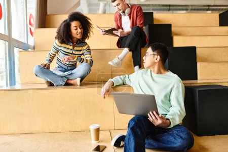 Eine multikulturelle Gruppe von Studenten, darunter ein schwarzes Mädchen, sitzt auf Stufen in einer Lernumgebung