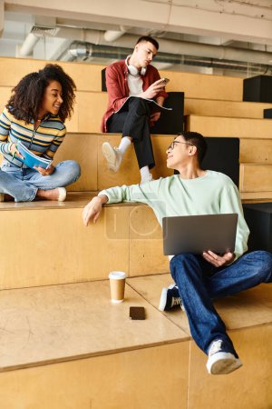 Photo for A group of people, including multicultural and African American students, sitting on bleachers with laptops - Royalty Free Image