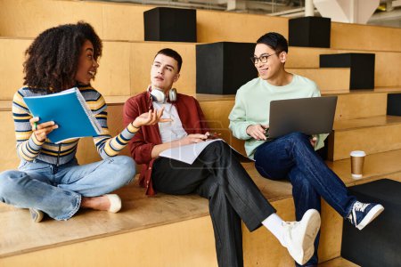Grupo multicultural de estudiantes sentados en escalones, trabajando juntos en ordenadores portátiles para proyectos universitarios o de secundaria