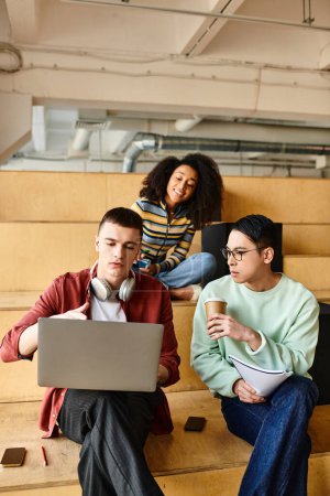 Multikulturelle Studentengruppe sitzt auf der Tribüne und benutzt Laptops für Bildungszwecke