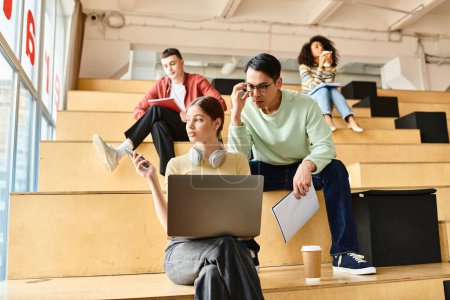 Estudiantes multiculturales estudian juntos en gradas con ordenadores portátiles en una institución educativa