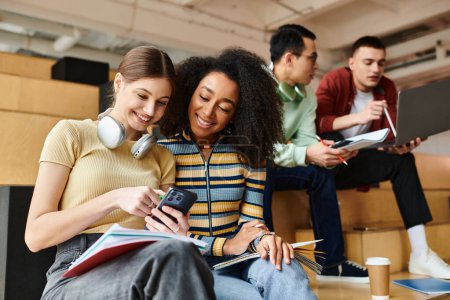 Estudiantes multiculturales sentados juntos, absortos en contenido en la pantalla de un teléfono celular, enfocándose intensamente en el dispositivo.