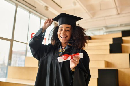 An African American woman proudly wears a graduation cap and gown, celebrating her academic achievements.