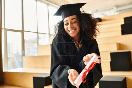 An African American woman in a graduation cap and gown celebrating academic success.