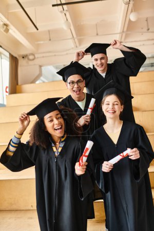 Diverso grupo de estudiantes en trajes de graduación y gorras sonriendo para una foto de grupo en el interior.