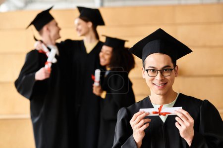 Un hombre diverso en un vestido de graduación triunfante tiene un diploma.