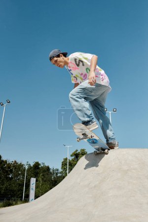 Junge Skater fährt an einem sonnigen Sommertag furchtlos mit seinem Skateboard die Rampe in einem Outdoor-Skatepark hinunter.