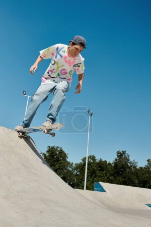 Un jeune patineur monte une planche à roulettes sur la rampe dans un skate park en plein air par une journée ensoleillée d'été.