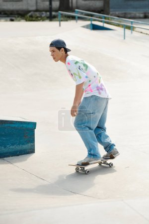 Young skater boy riding a skateboard down a cement ramp at a skate park on a sunny summer day.