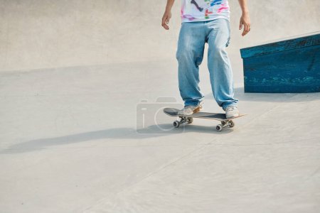 A young skater boy riding a skateboard down a cement ramp in a vibrant outdoor skate park on a sunny summer day.
