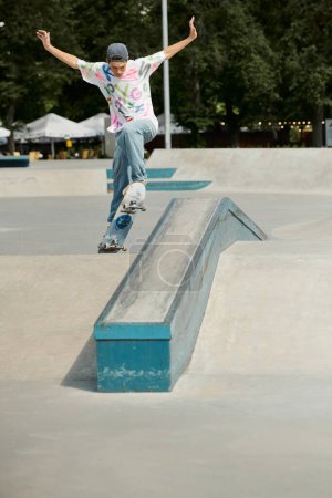 Foto de Un joven skater monta su monopatín por el lado empinado de una rampa en un vibrante parque de skate al aire libre en un soleado día de verano.. - Imagen libre de derechos