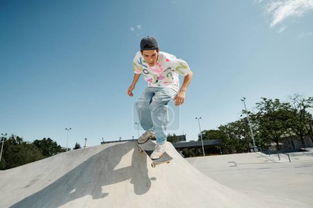 Téléchargez les photos : Un jeune patineur effectuant un impressionnant tour de skateboard sur le côté d'une rampe dans un skate park extérieur ensoleillé. - en image libre de droit