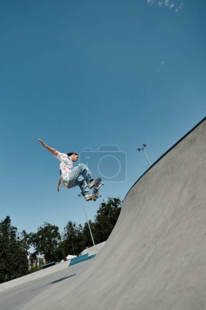 Foto de Un niño patinador sin miedo monta un monopatín hacia arriba en el lado de una rampa en un bullicioso parque de skate al aire libre en un día soleado de verano. - Imagen libre de derechos