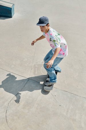 A young man effortlessly rides a skateboard down a cement ramp in a vibrant skate park on a sunny summer day.