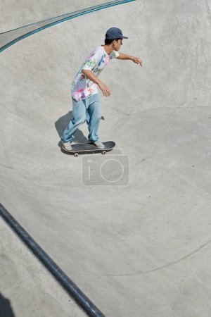 Ein junger Mann fährt in der Sommersonne eines Skateparks rücksichtslos mit einem Skateboard eine steile Rampe hinunter.