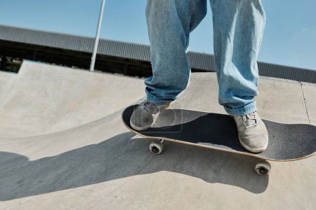 Téléchargez les photos : Un jeune patineur monte sans peur sa planche à roulettes sur le côté d'une rampe dans un skate park par une journée ensoleillée d'été. - en image libre de droit