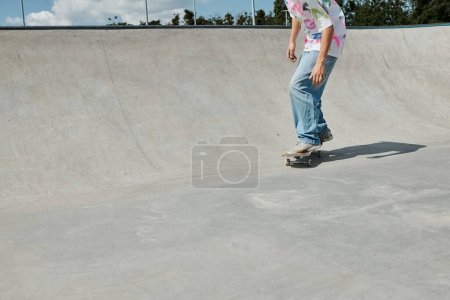 Photo for A young skater boy defies gravity as he rides his skateboard up the side of a ramp in a sunny skate park. - Royalty Free Image