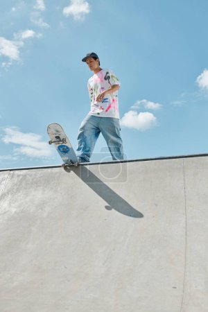 Photo for Young skater boy confidently riding skateboard up the side of a steep ramp in a sunny outdoor skate park. - Royalty Free Image