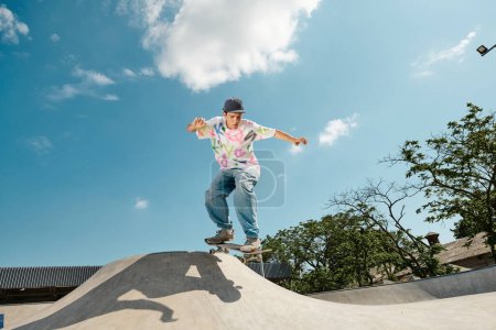 Photo for A young skater boy fearlessly rides a skateboard down the side of a ramp in a sunny outdoor skate park. - Royalty Free Image