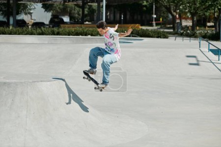 Foto de Un joven monta valientemente su monopatín por el lado empinado de una rampa en un parque de skate en un día soleado de verano.. - Imagen libre de derechos