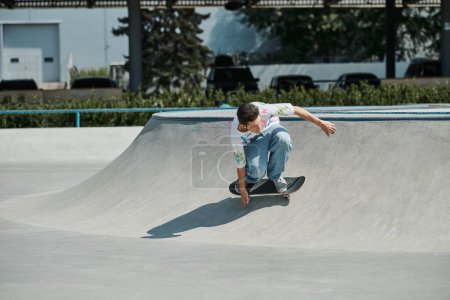 Ein junger Skater-Junge fährt an einem sonnigen Sommertag mit einem Skateboard eine steile Rampe in einem Outdoor-Skatepark hinauf.