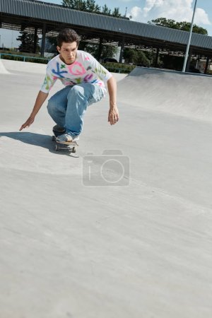 Photo for A young skater boy rides his skateboard down the side of a ramp in a sunny outdoor skate park on a summer day. - Royalty Free Image