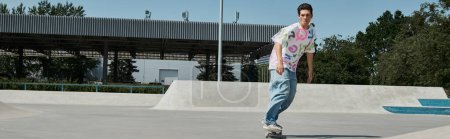 Photo for A young skater boy confidently rides his skateboard on top of a cement ramp at an outdoor skate park on a sunny day. - Royalty Free Image