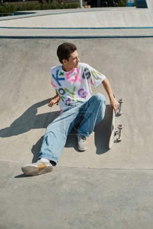 Foto de Un joven hábilmente monta su monopatín al lado de una rampa en un vibrante parque de skate al aire libre en un soleado día de verano.. - Imagen libre de derechos