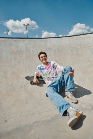 A young skater boy gracefully sits on his skateboard, skillfully maneuvering through the skate park on a sunny summer day.