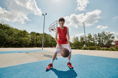 Ein junger Mann hält einen Basketball in der Hand, während er auf einem Platz steht und sich auf das Spiel vorbereitet.