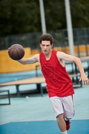 Ein junger Mann hält an einem sonnigen Tag selbstbewusst einen Basketball auf einem lebhaften Basketballfeld.
