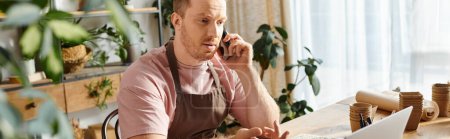 Ein Mann in einem Pflanzenladen, der an einem Tisch sitzt und mit einem Telefonat beschäftigt ist.