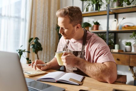 Ein Mann konzentriert sich auf seinen Laptop, umgeben von einem gemütlichen Arbeitsplatz mit einer Tasse Kaffee. Die perfekte Mischung aus Arbeit und Entspannung.