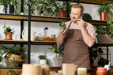 Foto de Un hombre en un delantal hablando en un teléfono celular en una tienda de plantas, encarnando el espíritu de poseer una pequeña empresa. - Imagen libre de derechos